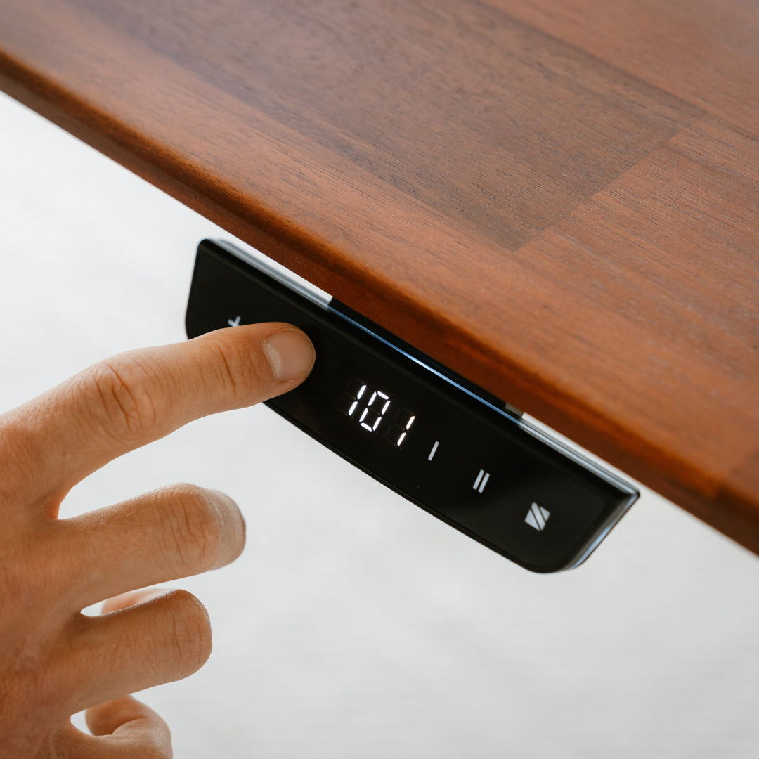 Hand pressing a digital clock on a wooden surface