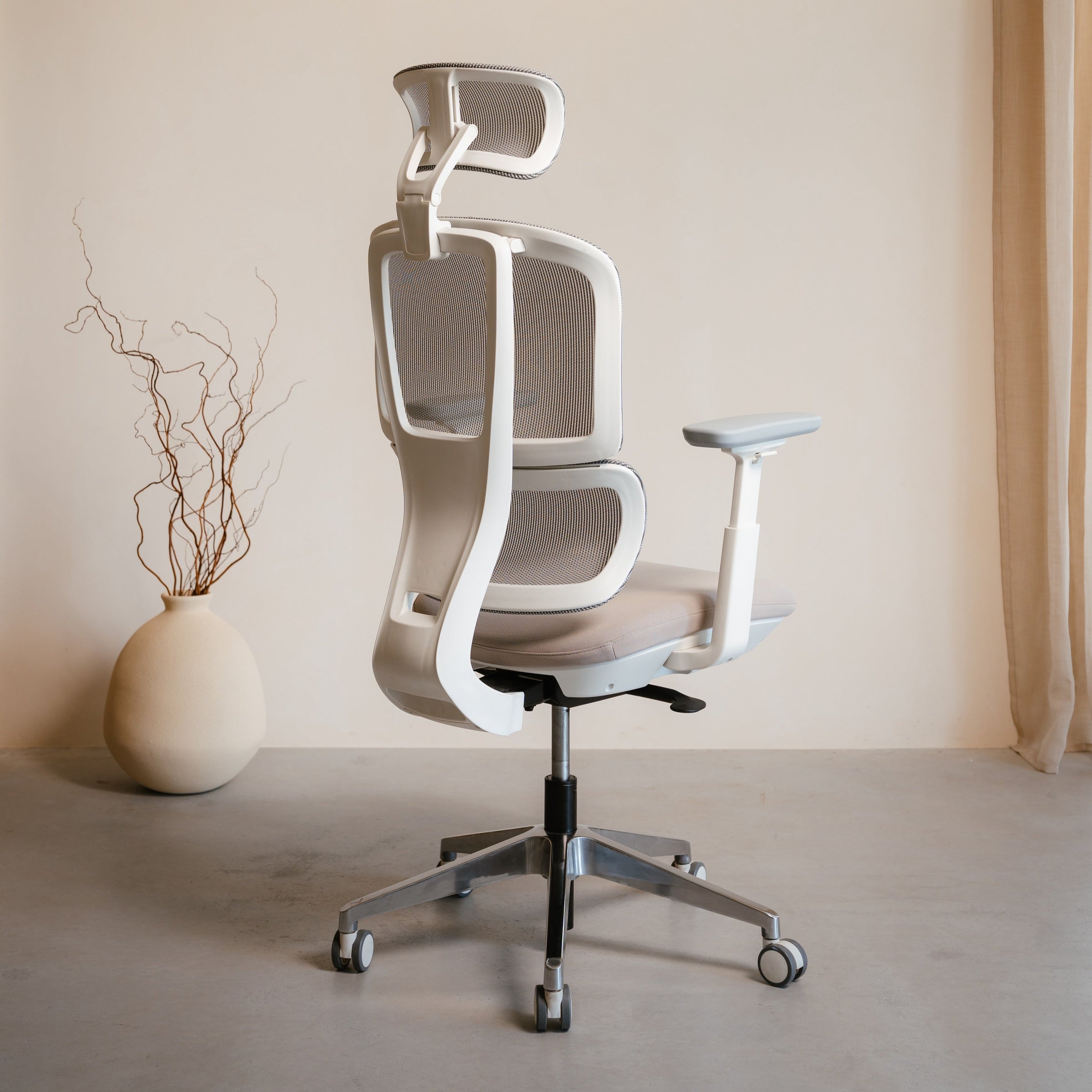 Modern office chair in a minimalistic room with a vase and plant.